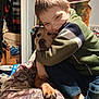animal, blanket, boy, candid, casual_clothing, child, comfort, cozy, dog, face, friendship, furniture, happy, home, hug, indoor, paw, pet, smile, sweater