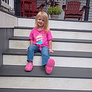 Isabella joined the competition — help win amazing prizes! child, girl, smile, pink_shirt, jeans, porch, steps, plant, red_chairs, outdoor, casual, sitting, happy, blonde_hair, footwear, crocs, wooden_chair, decoration, home, daylight
