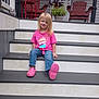child, girl, smile, pink_shirt, jeans, porch, steps, plant, red_chairs, outdoor, casual, sitting, happy, blonde_hair, footwear, crocs, wooden_chair, decoration, home, daylight