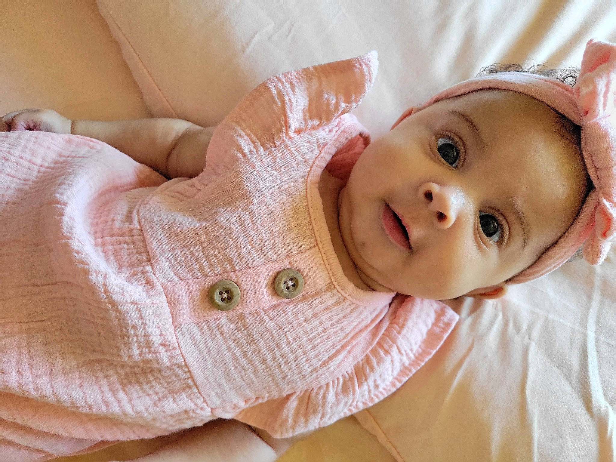 Aria is registered to the contest to win money with this photo: arm, baby, baby_toddler_clothing, cheek, comfort, eye, eyelash, face, finger, gesture, happy, headgear, lip, muscle, nose, person, pink, skin, smile, stomach