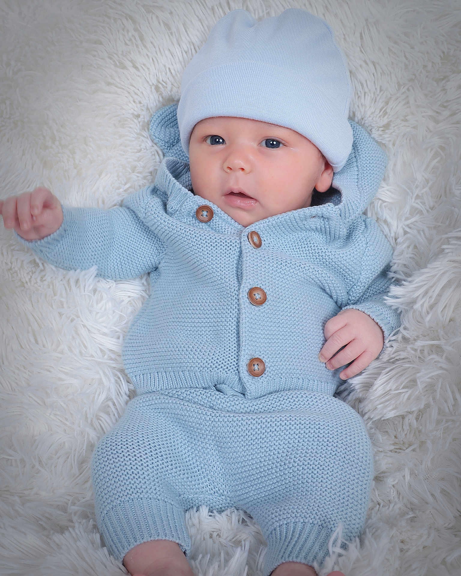 Dominic is registered to the contest to win money with this photo: baby, infant, blue_clothing, knitted_outfit, hat, blanket, fluffy, lying_down, cute, portrait, soft_texture, newborn, child, warm_clothing, indoor, small_hands, baby_face, cozy, comfort, sleepwear