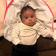 Legacy Howard joined the competition — help win amazing prizes! baby, infant, face, towel, white_towel, clothing, cream_top, black_pants, indoors, lying_down, person, cute, curious, young_child, child, soft_texture, fabric, relaxed, big_eyes, portrait
