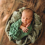 Colter joined the competition — help win amazing prizes! newborn, baby, sleeping, wrapped, green_cloth, basket, blanket, wooden_floor, peaceful, portrait, infant, soft_texture, cozy, resting, head, face, hands, closeup, indoor, cute