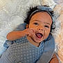Willow is registered to the contest to win money with this photo: baby, infant, smiling, happy, curly_hair, headband, blue_clothing, knitted_outfit, blanket, soft_texture, lying_down, portrait, cute, child, indoor, closeup, baby_girl, comfortable, warm, expressive_face