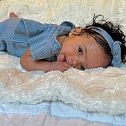 Willow is registered to the contest to win money with this photo: baby, child, infant, blue_clothing, headband, curly_hair, blanket, soft_texture, lying_down, indoor, cute, portrait, skin, hand, face, eyes, smile, cozy, comfort, young