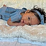 baby, child, infant, blue_clothing, headband, curly_hair, blanket, soft_texture, lying_down, indoor, cute, portrait, skin, hand, face, eyes, smile, cozy, comfort, young