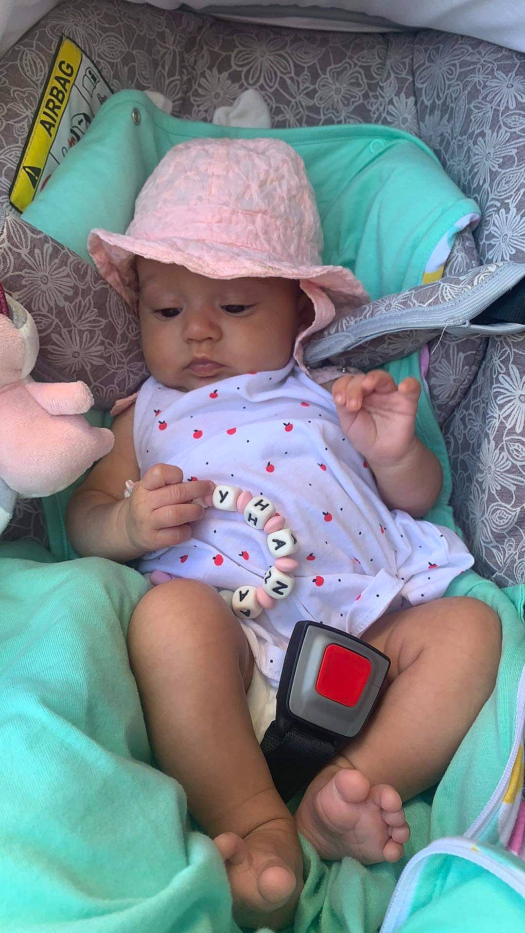 Lyhana participe au concours pour gagner de l'argent avec cette photo : arm, baby, baby_toddler_clothing, baseball_cap, blue, cap, child, comfort, finger, fun, green, hand, hat, headgear, headwear, human_body, lap, person, pink, skin