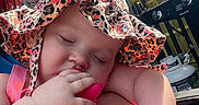 Annalise joined the competition — help win amazing prizes! baby, child, hat, sun_hat, outdoor, grill, propane_tank, fence, greenery, hand, arm, sleeping, pink_clothing, toy, peaceful, skin, person, summer, daylight, closeup