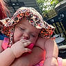 baby, child, hat, sun_hat, outdoor, grill, propane_tank, fence, greenery, hand, arm, sleeping, pink_clothing, toy, peaceful, skin, person, summer, daylight, closeup