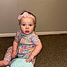 baby, child, infant, headband, pink, pajamas, floral_pattern, stuffed_animal, blue, carpet, floor, sitting, indoor, wall, person, cute, toy, young_child, portrait, looking_at_camera