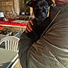 Alpha a rejoint le concours — aidez-le/la à gagner de superbes lots ! black_dog, casual, chair, cute, dog, domestic, face, glasses, hand, holding, indoor, jacket, nose_ring, person, pet, puppy, stone_wall, table, warm_lighting, window