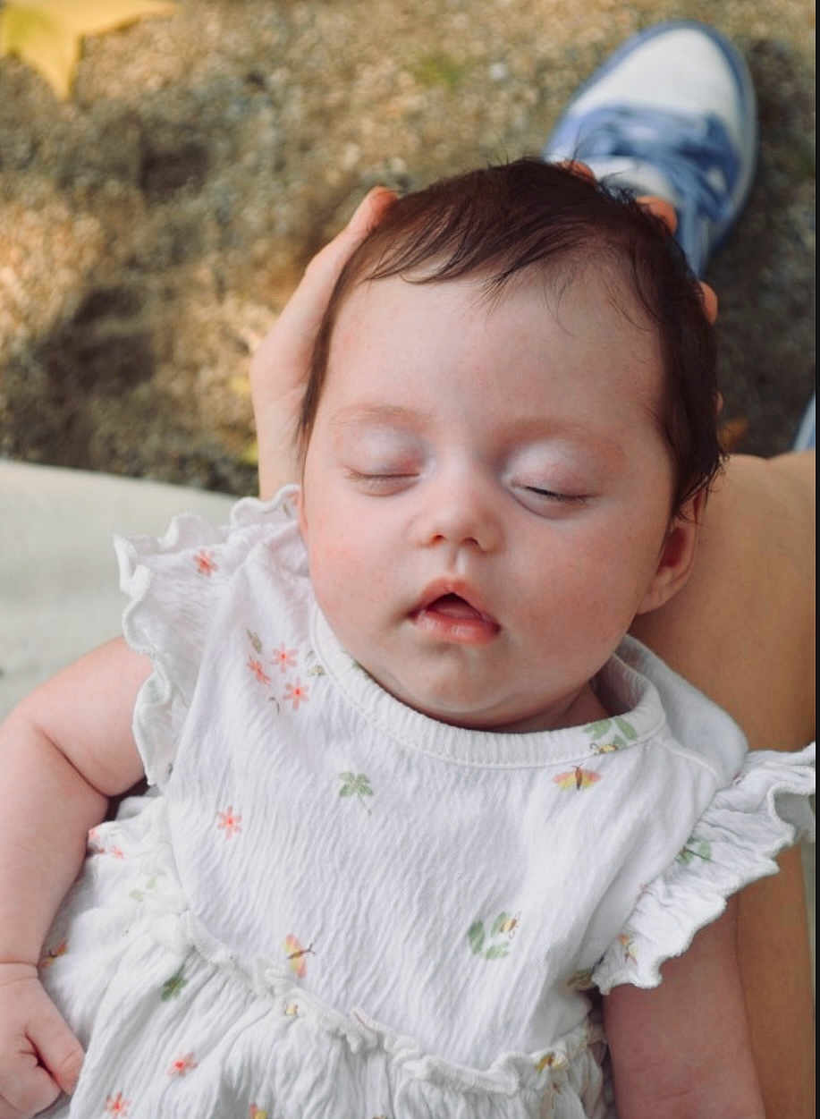 Constance a rejoint le concours — aidez-le/la à gagner de superbes lots ! baby, child, closed_eyes, cute, face, floral_pattern, footwear, hand, infant, outdoor, peaceful, person, portrait, resting, sleeping, sneaker, soft_skin, tender, white_dress, young