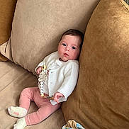 Constance a rejoint le concours — aidez-le/la à gagner de superbes lots ! baby, blanket, child, clothing, comfort, couch, cozy, cute, home, indoor, infant, pacifier, person, pillow, pink_pants, relaxing, seated, socks, soft_furnishings, white_cardigan
