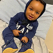 Tylan joined the competition — help win amazing prizes! baby, child, smiling, hoodie, navy_blue, shoes, pacifier, bed, pillow, striped, indoor, cute, person, sitting, footwear, young_child, infant, happy, clothing, portrait