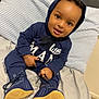 baby, child, smiling, hoodie, navy_blue, shoes, pacifier, bed, pillow, striped, indoor, cute, person, sitting, footwear, young_child, infant, happy, clothing, portrait