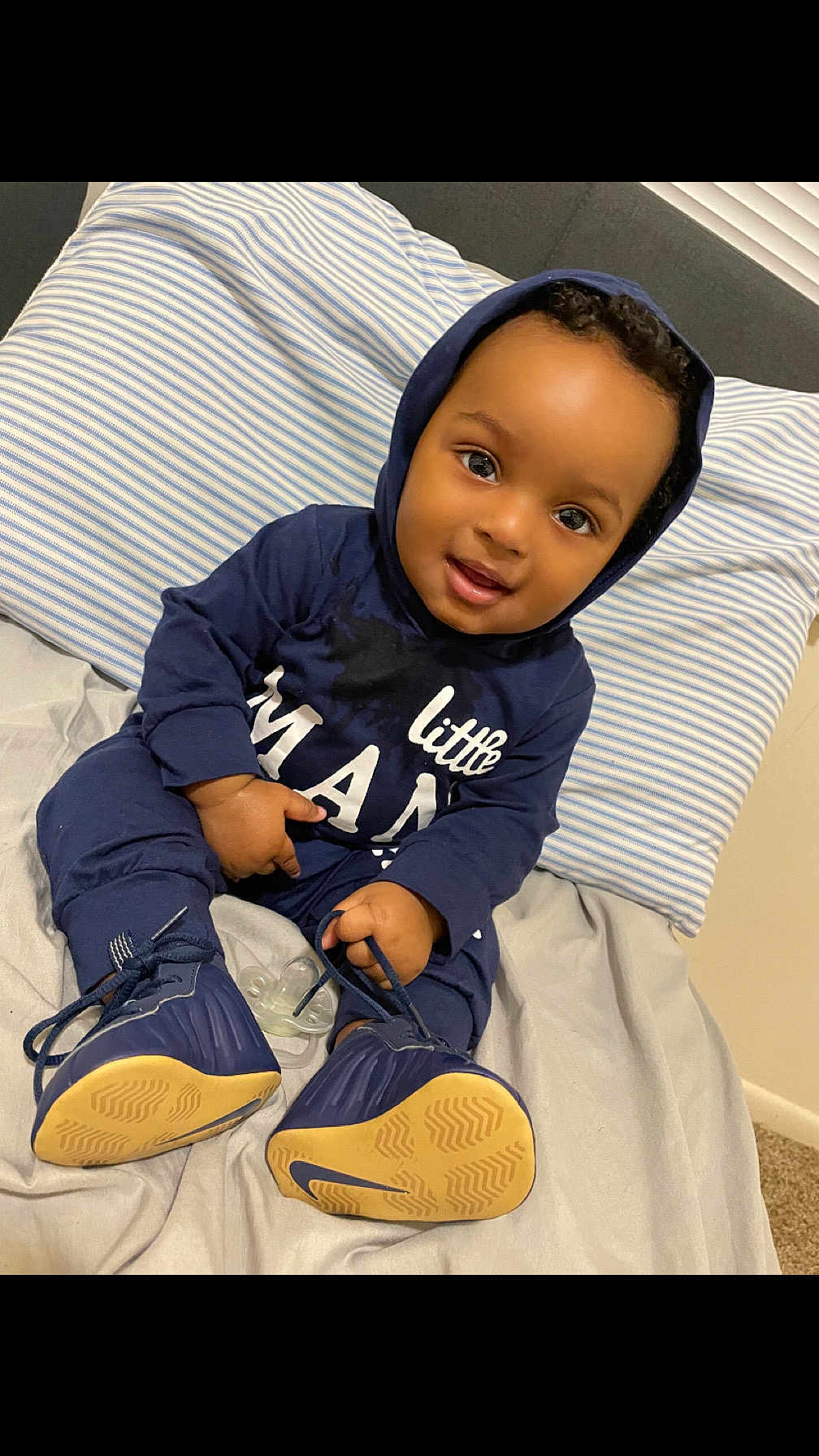Tylan joined the competition — help win amazing prizes! baby, child, smiling, hoodie, navy_blue, shoes, pacifier, bed, pillow, striped, indoor, cute, person, sitting, footwear, young_child, infant, happy, clothing, portrait
