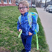Xavier joined the competition — help win amazing prizes! child, boy, glasses, backpack, blue_clothing, nike, grass, sidewalk, brick_building, car, outdoor, casual, walking, smiling, daylight, urban, person, trees, jacket, pants