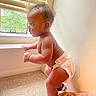 baby, child, diaper, standing, climbing, profile, indoor, window, sunlight, blanket, pink_blanket, carpet, home, wall, shutters, portrait, infant, toddler, side_view, natural_light