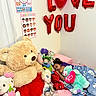 child, sleeping, stuffed_animals, teddy_bear, balloons, love_balloons, bedroom, blanket, pillow, plush_toys, pink_bed, wall_posters, red_tutu, hello_kitty, elsa_doll, cozy, indoor, curtain, happy, cute