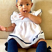 Taige joined the competition — help win amazing prizes! baby, child, infant, girl, dress, headband, bow, socks, sitting, couch, furniture, indoors, cute, adorable, hand, face, expression, young, person, portrait