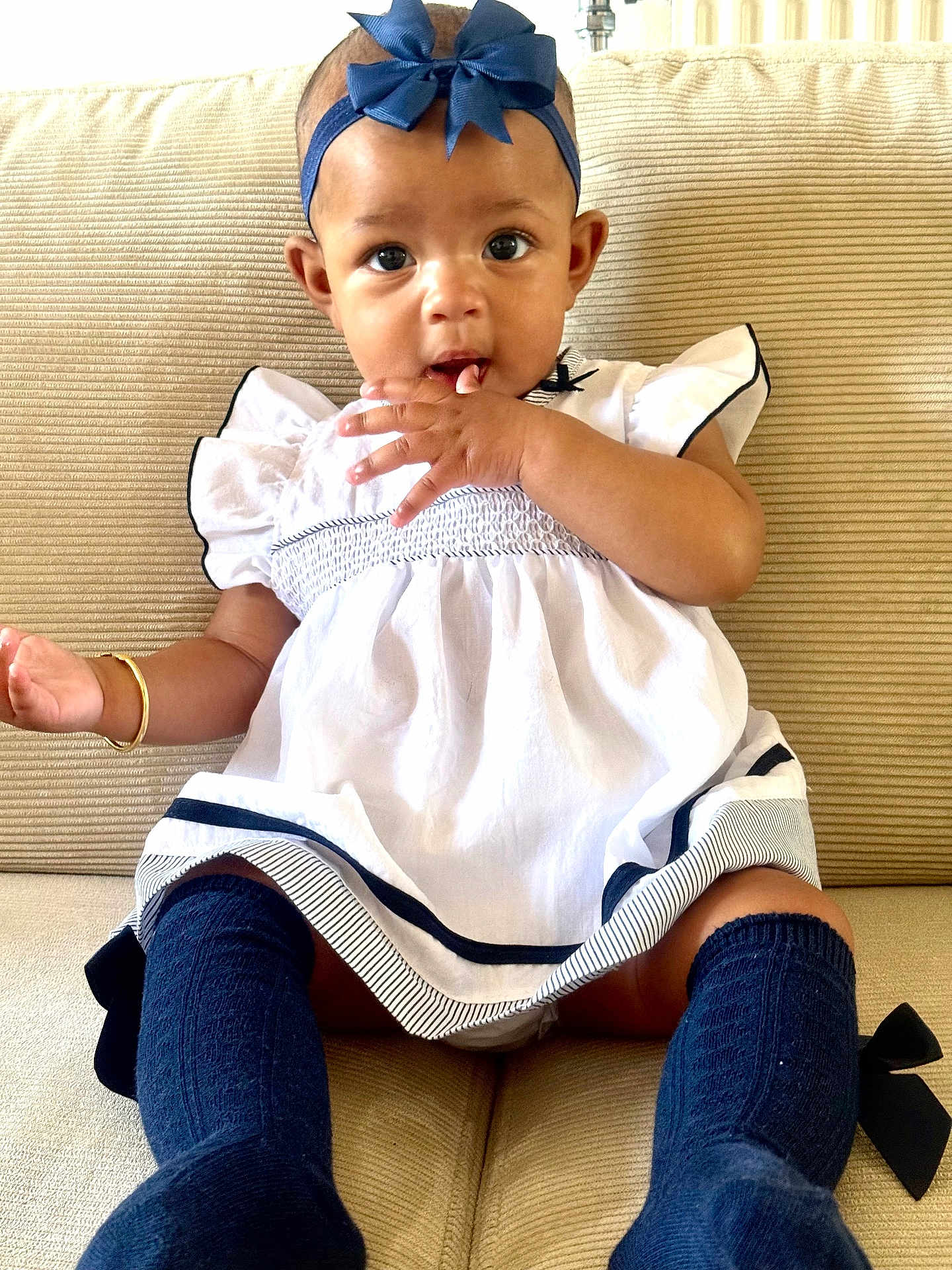 Taige joined the competition — help win amazing prizes! baby, child, infant, girl, dress, headband, bow, socks, sitting, couch, furniture, indoors, cute, adorable, hand, face, expression, young, person, portrait