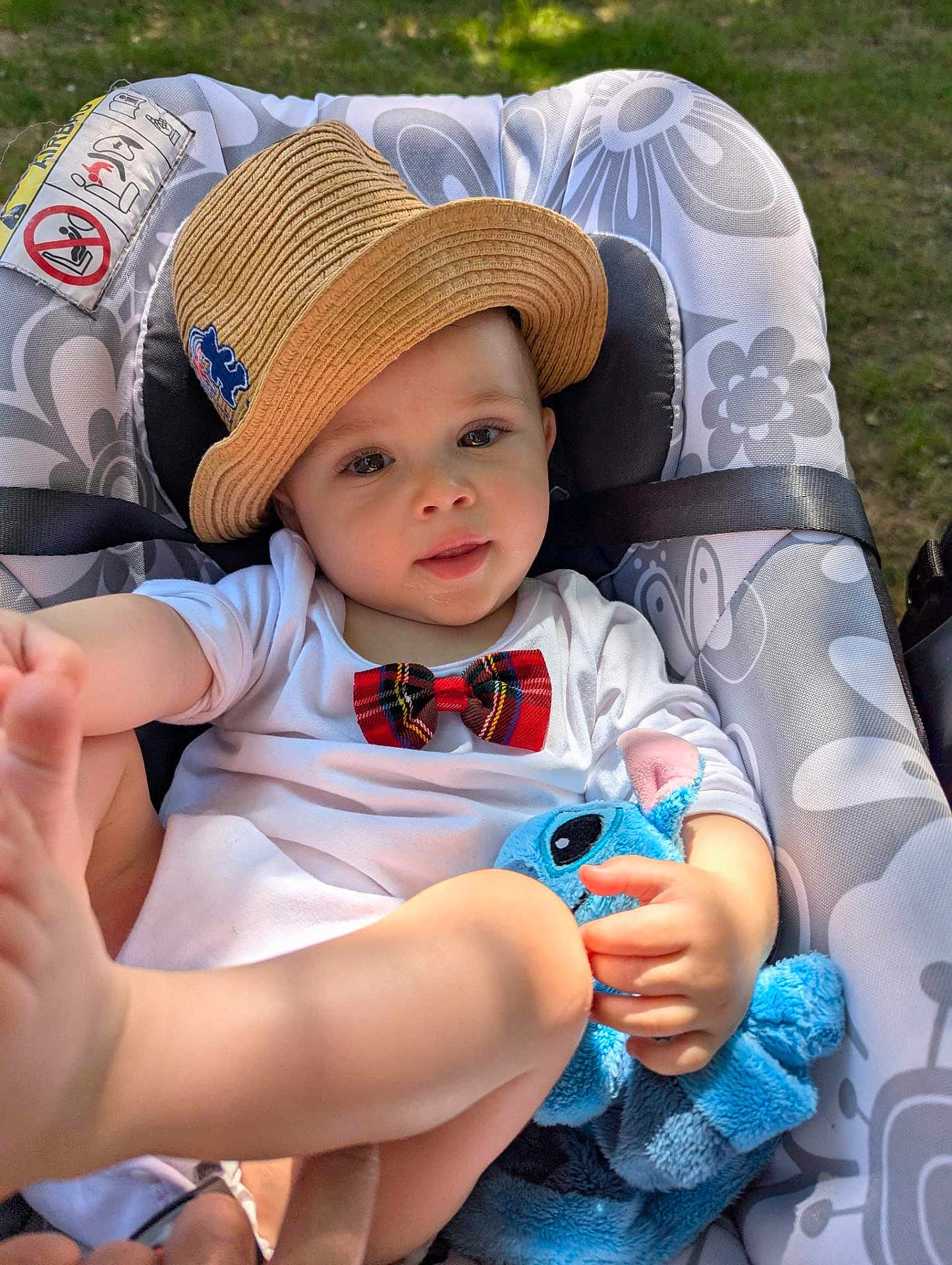 Castiel participe au concours pour gagner de l'argent avec cette photo : baby, child, hat, bow_tie, plush_toy, blue_toy, baby_seat, outdoor, grass, foot, hand, clothing, cute, playful, smiling, infant, face, portrait, sunlight, relaxing