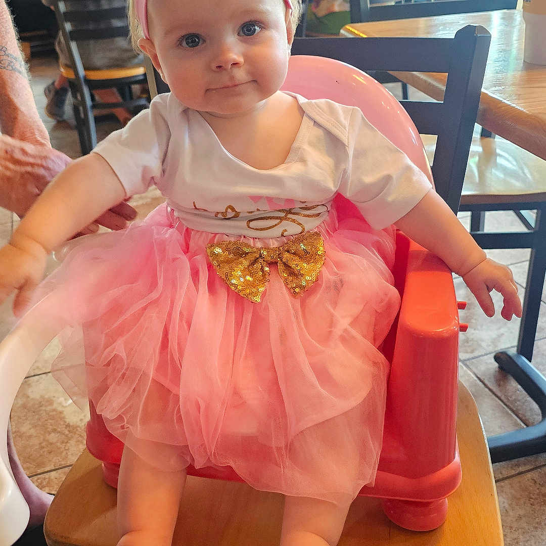 Dawn joined the competition — help win amazing prizes! baby, background, casual, chair, child, cute, floor_tile, golden_bow, headband, high_chair, indoor, people, person, pink, restaurant, seated, smiling, socks, table, tutu