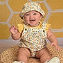 Malia is registered to the contest to win money with this photo: baby, child, smiling, hat, floral_outfit, yellow, background, woven_mat, happy, sitting, cute, portrait, infant, footwear, studio_photo, patterned_background, chubby_arms, chubby_legs, bright, indoor