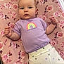 Gracie is registered to the contest to win money with this photo: baby, infant, child, purple_shirt, rainbow, polka_dot_pants, floral_pattern, changing_pad, indoor, natural_light, curious_expression, window_blinds, basket, soft_fabric, person, cute, portrait, lying_down, pastel_colors, home