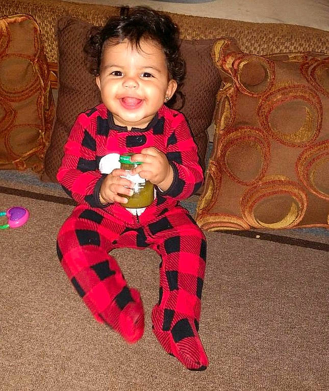 Avani is registered to the contest to win money with this photo: baby, child, christmas, design, holiday, joy, pattern, person, pink, plaid, play, sitting, smile, tartan, toddler