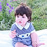 baby, child, infant, sitting, blanket, outdoor, garden, flowers, purple_flowers, greenery, curly_hair, blue_dress, checkered, cute, rosy_cheeks, portrait, nature, soft_light, peaceful, young