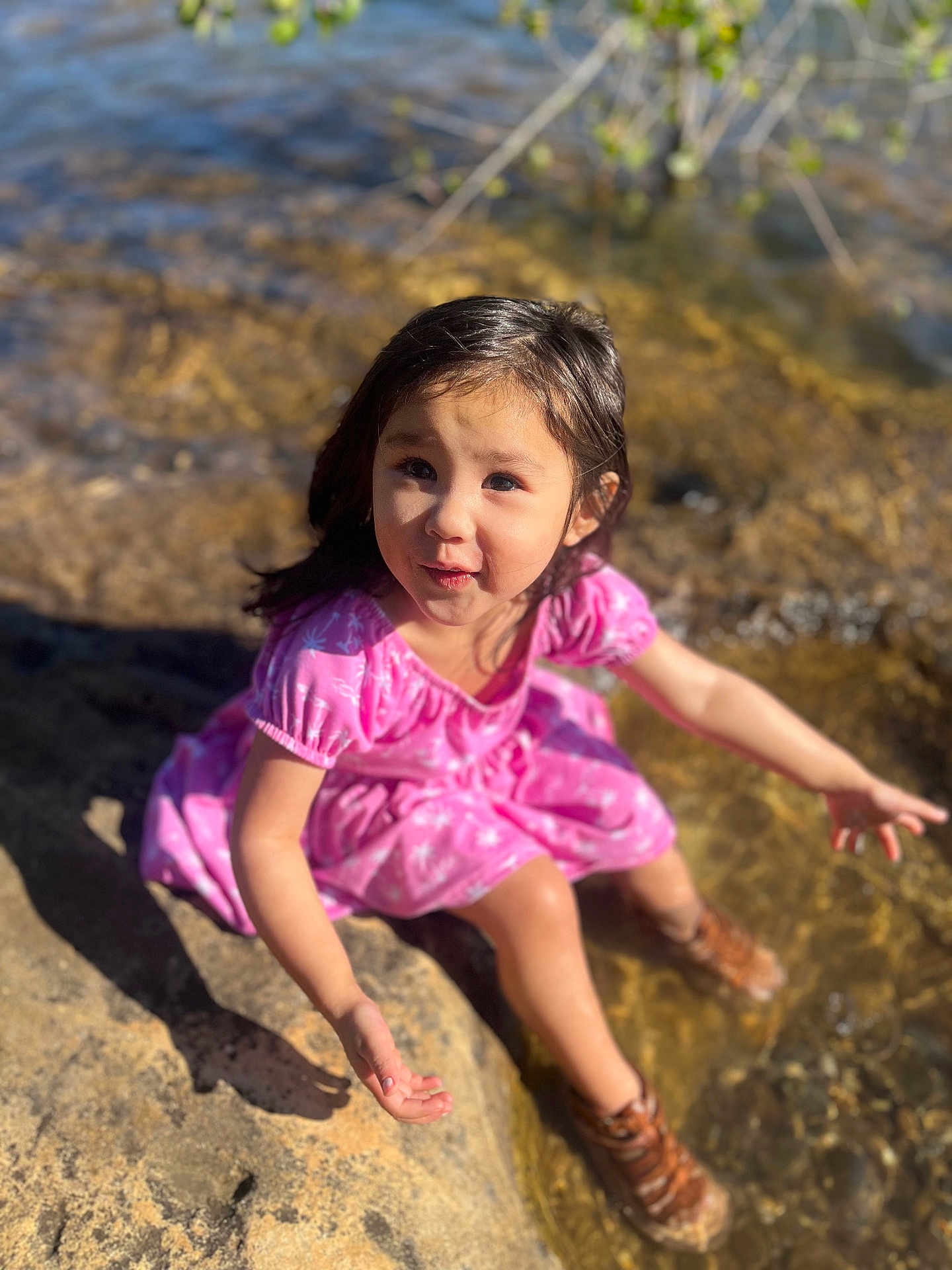 Zara is registered to the contest to win money with this photo: child, girl, pink_dress, water, rocks, outdoor, nature, boots, sunlight, shadow, playful, curious, sitting, summer, daylight, happy, portrait, young, water_edge, exploration