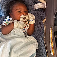 Michael is registered to the contest to win money with this photo: baby, infant, pacifier, blanket, mittens, car_seat, clothing, cute, sleeping, comfort, child, newborn, soft, resting, indoor, person, portrait, babywear, cozy, toddler