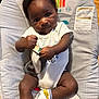 baby, baby_seat, child, clothing, cute, determined, expression, face, floor, hands, indoor, infant, legs, monkey_graphic, onesie, pattern, rainbow, socks, strap, wood_floor