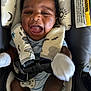 baby, black_hair, car_seat, child, closeup, cute, face, happy, indoor, infant, mittens, mouth_open, onesie, padded_straps, person, seatbelt, smiling, stripes, warning_label, young_child