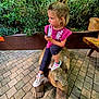 Gabrielle a rejoint le concours — aidez-le/la à gagner de superbes lots ! brick_patio, casual_clothing, child, curious, daylight, drink, girl, greenery, hair_tied, nature, outdoor, pink_shirt, playful, portrait, side_view, sitting, sneakers, straw, tortoise_sculpture, wooden_bench