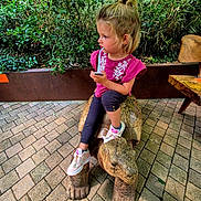 Gabrielle participe au concours pour gagner de l'argent avec cette photo : brick_patio, casual_clothing, child, curious, daylight, drink, girl, greenery, hair_tied, nature, outdoor, pink_shirt, playful, portrait, side_view, sitting, sneakers, straw, tortoise_sculpture, wooden_bench