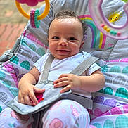 Truee joined the competition — help win amazing prizes! baby, smiling, infant, baby_seat, toy, rainbow, patterned_clothing, sitting, straps, cute, outdoor, playful, colorful, happy, child, soft_toy, curly_hair, face, bright, comfort