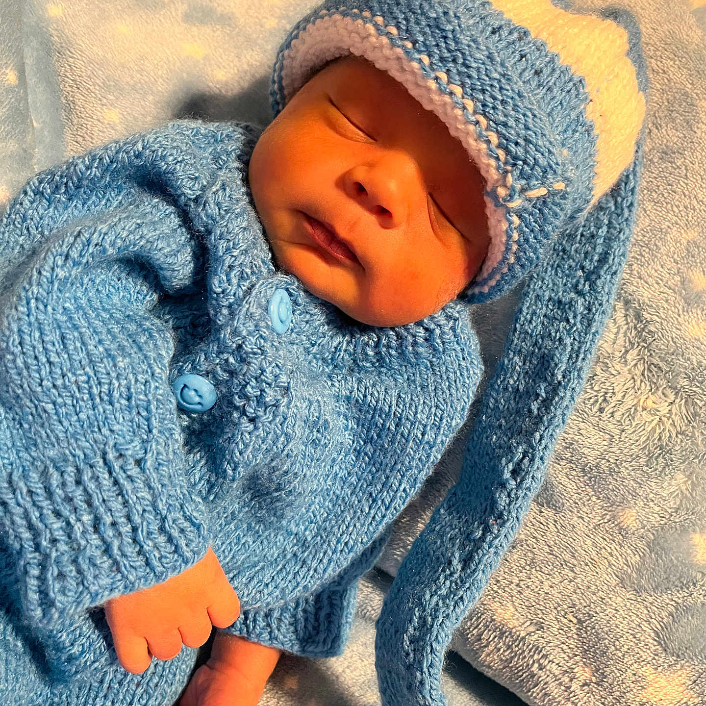 Pablo is registered to the contest to win money with this photo: baby, blanket, blue_clothing, child, cozy, cute, foot, hand, indoors, infant, knitted_hat, knitted_sweater, newborn, peaceful, portrait, resting, sleep, sleeping, soft_texture, warm