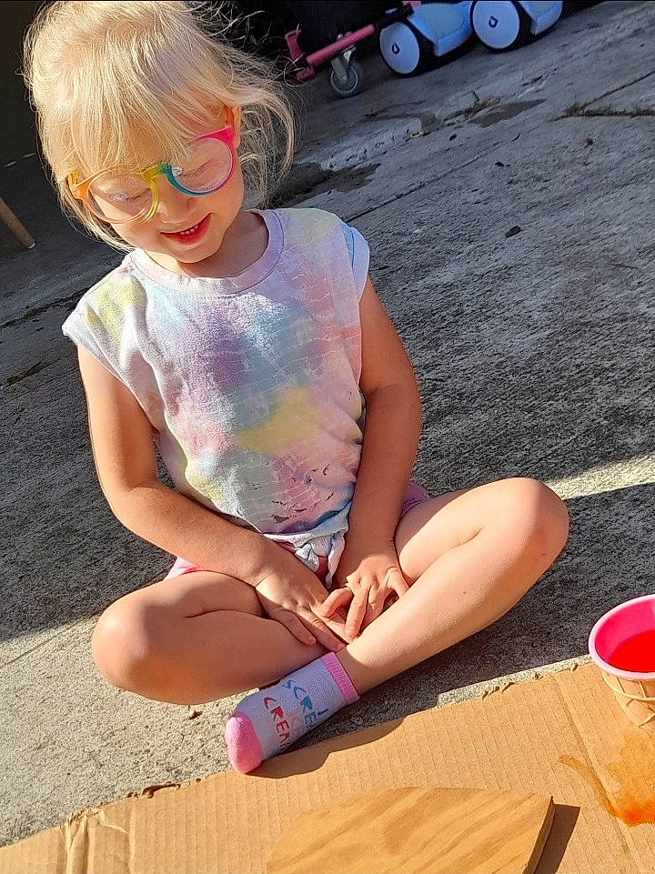 Amaya is registered to the contest to win money with this photo: barefoot, child, eyewear, foot, fun, hairstyle, happy, human_leg, leisure, people, person, public_space, shorts, sitting, smile, summer, thigh, tire, toddler, wheel