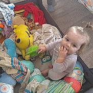 Laila joined the competition — help win amazing prizes! baby, child, playpen, stuffed_toys, blanket, plush_toy, toy_turtle, toy_pikachu, mesh, sitting, indoor, child_playing, hand_in_mouth, colorful, soft_toys, person, infant, cute, casual_clothing, floor