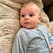 Raphaël a rejoint le concours — aidez-le/la à gagner de superbes lots ! baby, infant, child, blue_onesie, blanket, soft_texture, face, portrait, indoor, comfort, sleepwear, couch, curious, young_child, closeup, skin, head, eyes, hand, cozy