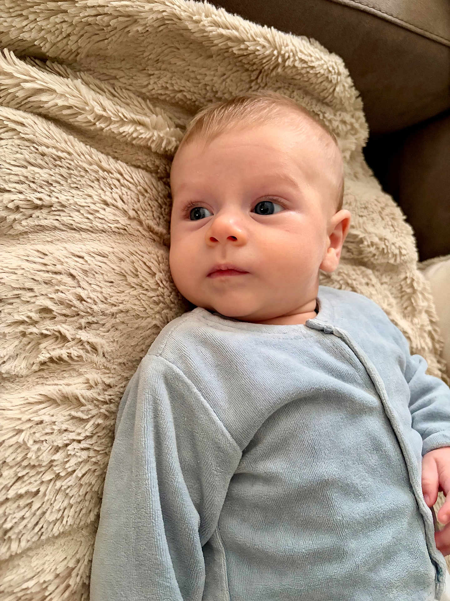 Raphaël a rejoint le concours — aidez-le/la à gagner de superbes lots ! baby, infant, child, blue_onesie, blanket, soft_texture, face, portrait, indoor, comfort, sleepwear, couch, curious, young_child, closeup, skin, head, eyes, hand, cozy