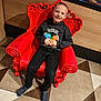 boy, bright_colors, casual_clothing, child, comfortable, cute, floor_tiles, furniture, happy, home, indoor, person, pokemon_hoodie, portrait, red_chair, seated, smiling, striped_socks, wooden_wall, young