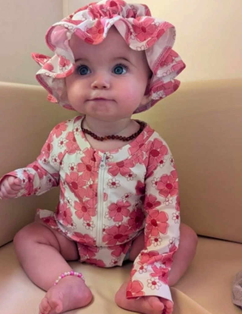 Milaya participe au concours pour gagner de l'argent avec cette photo : baby, child, infant, sitting, hat, floral_pattern, bracelet, necklace, pink, white, couch, indoor, cute, clothing, accessory, portrait, face, feet, expression, young