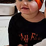 Milaya participe au concours pour gagner de l'argent avec cette photo : baby, child, pumpkin_hat, orange_and_black, black_shirt, yellow_socks, sitting, happy, smiling, cute, indoor, floor, hand, festive_clothing, face, eyes, cheeks, infant, clothing, portrait