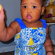 Salimatou Bah joined the competition — help win amazing prizes! toddler, child, dress, blue, yellow, patterned_clothing, indoor, curious, braided_hair, person, face, skin, hand, floor, pottery, plant, decor, expression, young_child, standing