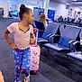 Fatimatou Bah joined the competition — help win amazing prizes! child, airport, waiting_area, suitcase, butterfly_pattern, leggings, sandals, chairs, people, travel, signage, carpet, security_camera, recycling_bin, lighting, pose, hair_bun, casual_clothing, indoor, public_space