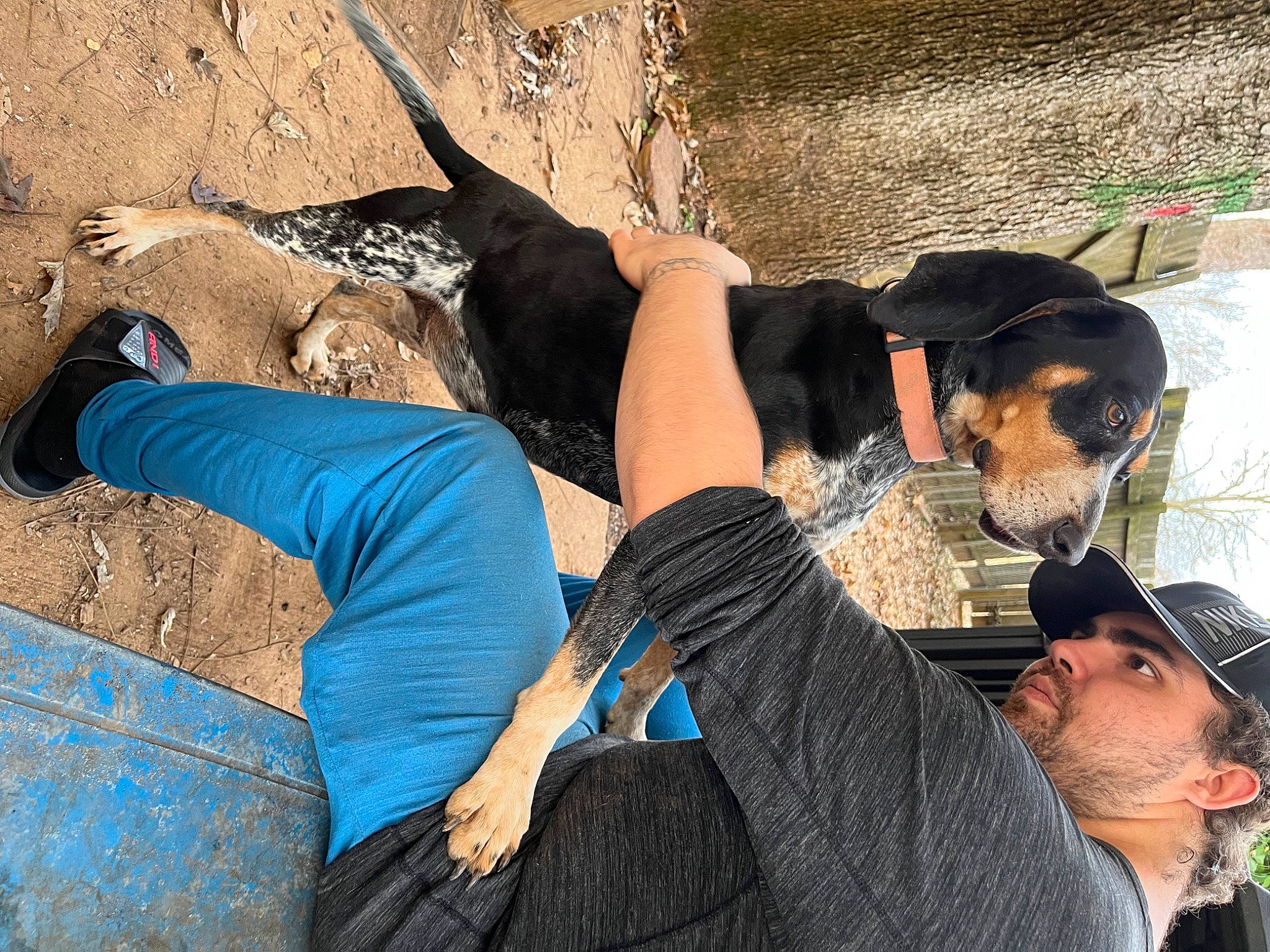 Quincy is registered to the contest to win money with this photo: adventure, baseball_cap, beard, cap, carnivore, dog, elbow, electric_blue, event, fun, hat, human_leg, knee, landscape, leisure, recreation, sitting, t_shirt, thigh, trunk