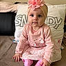 baby, child, pink_clothing, headband, flower, sitting, pillow, sofa, blanket, indoors, cute, portrait, toddler, face, eyes, hands, feet, soft_toys, cozy, smiling